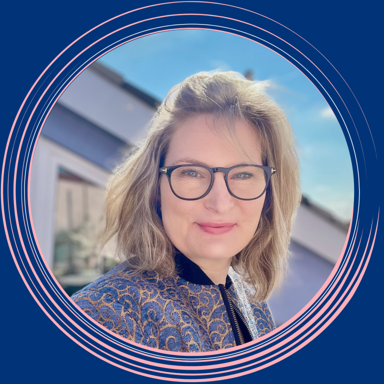Catrin Strüh-Flament Frau mit blonden Haaren und Brille lächelt vor einer hellen, urbanen Kulisse. Digitale Produkte, Online Schulungen, Projektkoordination, VA
