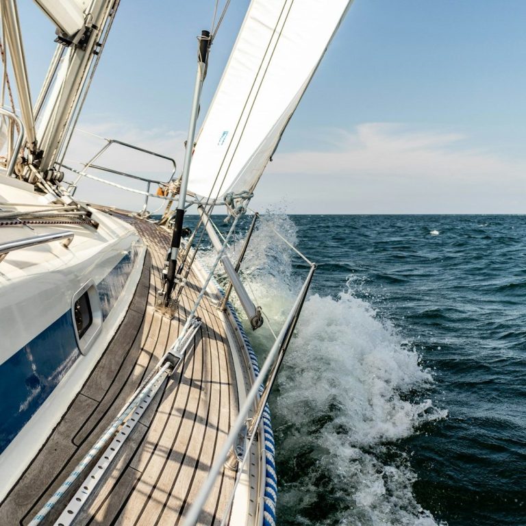 Segelboot auf ruhiger See, mit Wellen, die gegen die Seite schlagen.